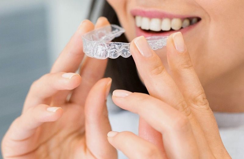 Patient holding a clear aligner and smiling