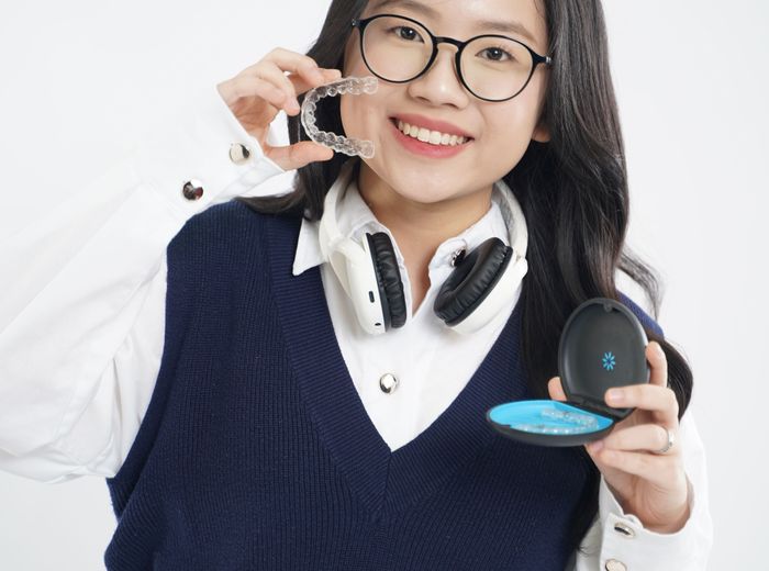 Smiling woman holding her clear aligners